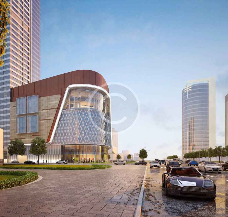 Calle de una ciudad moderna en la que se ve un edificio de cristal curvado, posiblemente de construcción prefabricada, con torres de gran altura al fondo y coches aparcados a lo largo de la calzada.