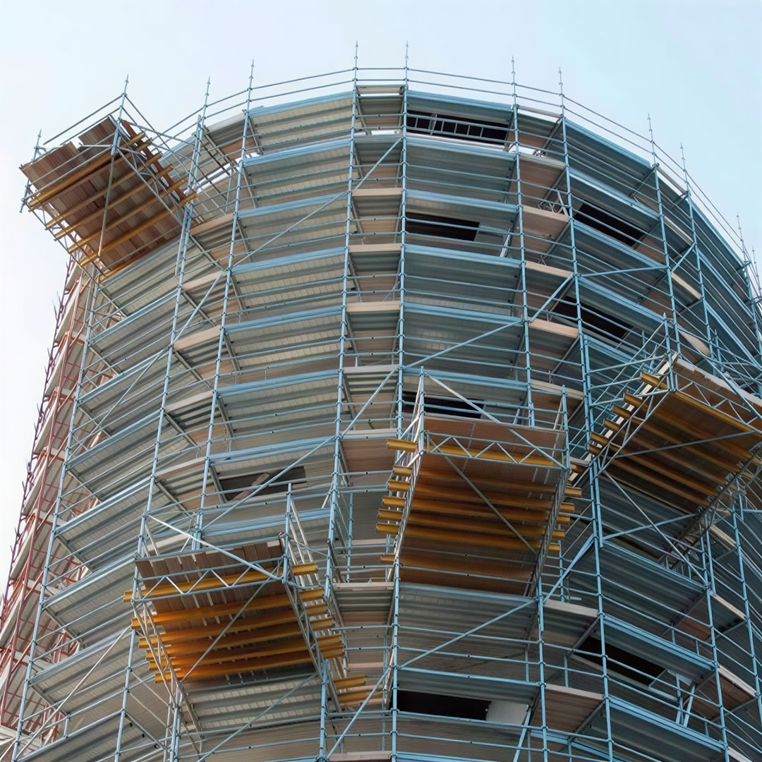 Un edificio cilíndrico está rodeado de un amplio andamiaje con múltiples plataformas a diferentes alturas.