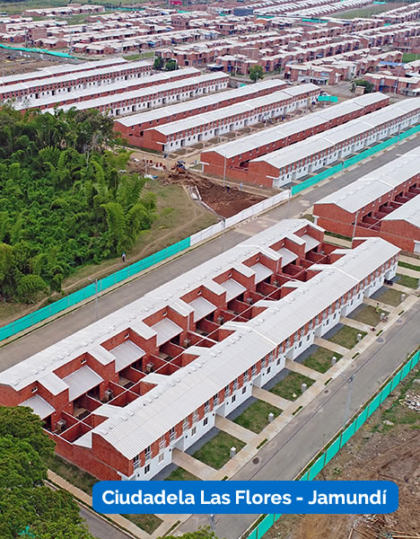 Vista aérea de hileras de edificios residenciales rojos y blancos idénticos en Ciudadela Las Flores, Jamundí, con una zona verde a la izquierda.