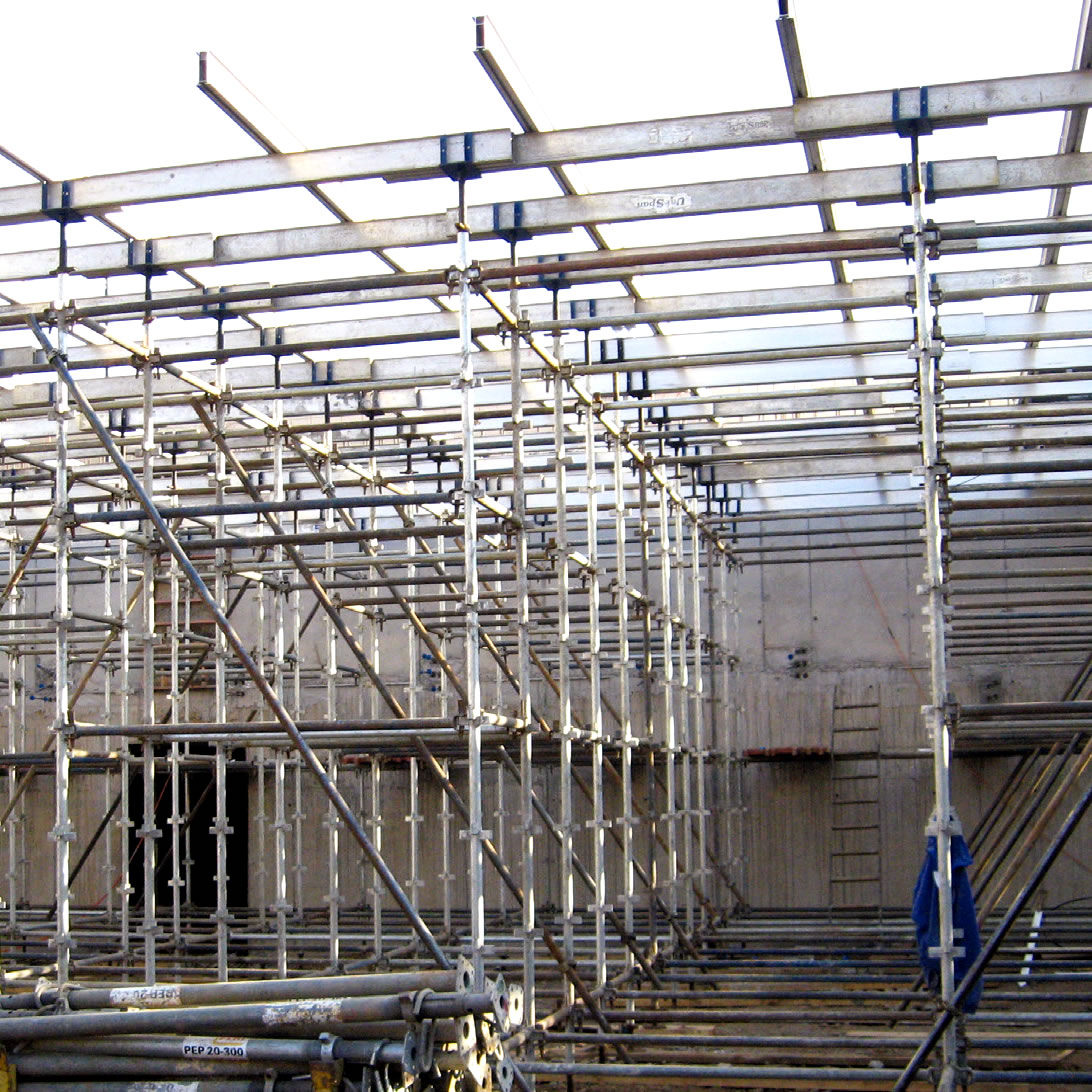 Andamio metálico montado en una obra, con barras horizontales y verticales formando una estructura reticular alrededor de un edificio de hormigón.