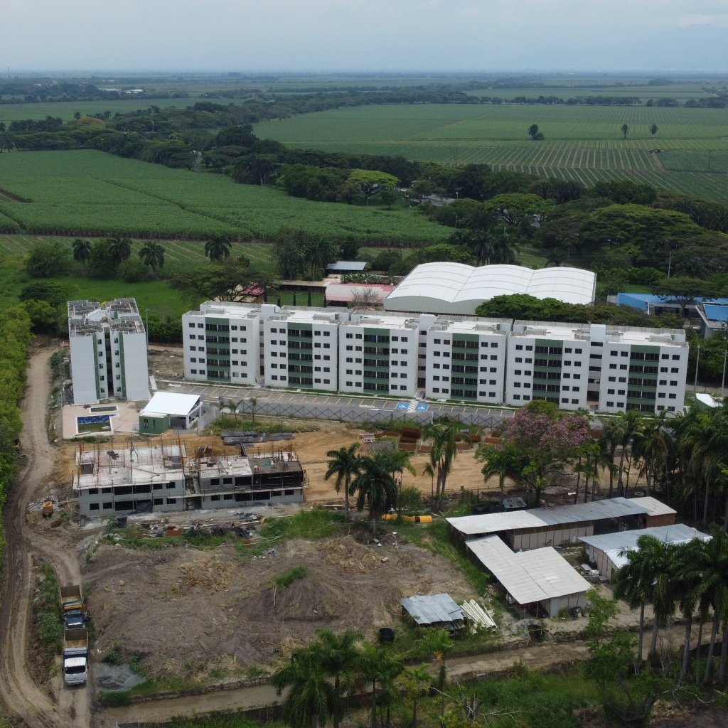Vista aérea de una obra con varios edificios de varias plantas que utilizan encofrados Unispan a punto de terminarse, rodeados de tierras de cultivo y árboles en una zona rural.