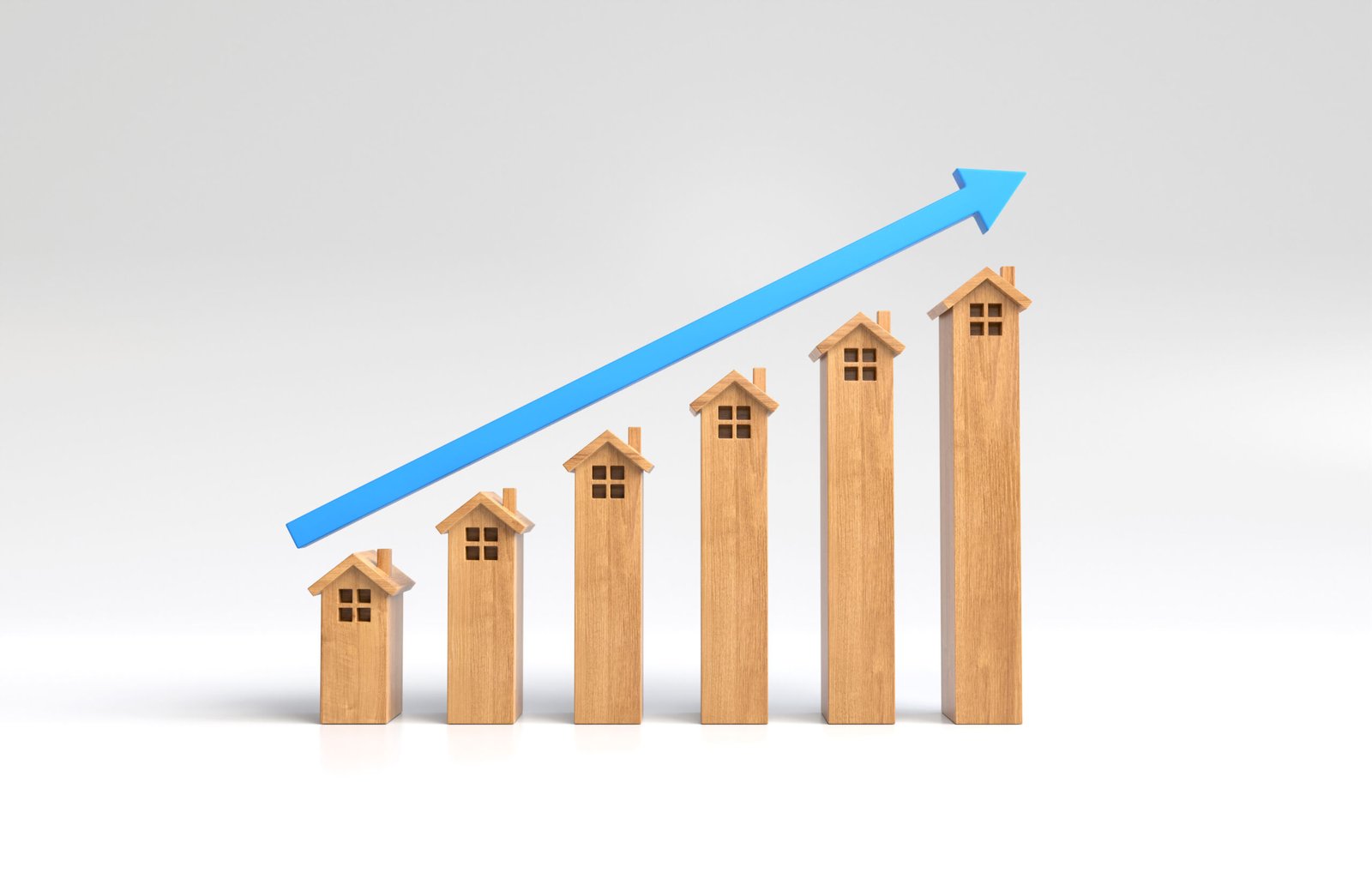 Seis maquetas de casas de madera dispuestas en orden ascendente de altura, con una flecha azul que apunta hacia arriba sobre ellas, lo que simboliza el crecimiento o las tendencias al alza en el sector de la vivienda, el mercado inmobiliario o la tasa hipotecaria.